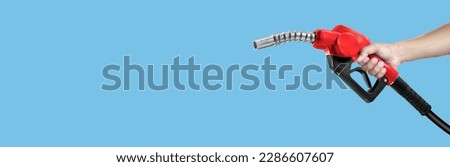 Hands holding Fuel nozzle on light blue background Royalty-Free Stock Photo #2286607607