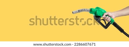 Hands holding Fuel nozzle on yellow background Royalty-Free Stock Photo #2286607671