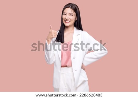 Portrait happy Asian woman shows thumb up and looking at the camera on pink background.
