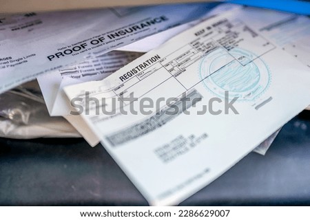 Proof of insurance and vehicle registration documents in the glove compartment of a car.  Royalty-Free Stock Photo #2286629007