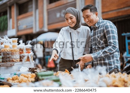 beautiful muslim woman and man are shopping in a food stall or street vendor during ramadan Royalty-Free Stock Photo #2286640475