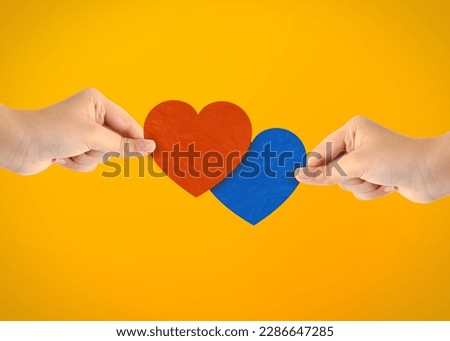 Two arms holding blue and red paper heart shape