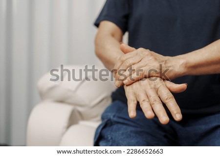 Close up hands of asian senior elderly woman with parkinson's disease symptom, hand numbness, finger lock, hand pain. Mental health and elderly care concept