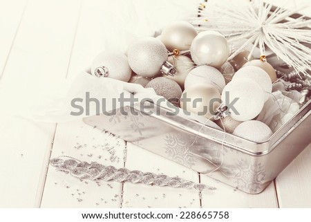 Retro style image of  silver Christmas ornaments in a silver box over white wooden background. Selective focus, shallow DoF, vintage filters