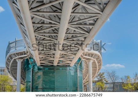 Underside of pedestrian walkway across street connected to glass building. Royalty-Free Stock Photo #2286675749
