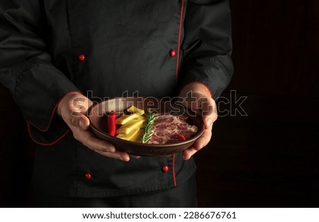 Professional chef serves a serving plate with sliced ham and cheese. Dark free space for recipe or menu