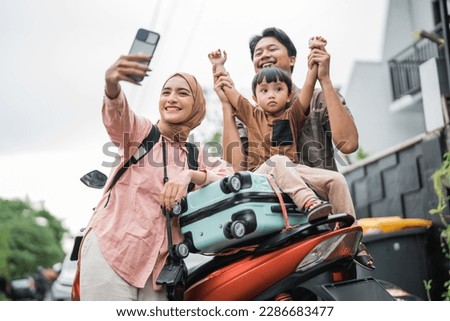 asian muslim family riding motorbike scooter together traveling with kid take selfie with smartphone