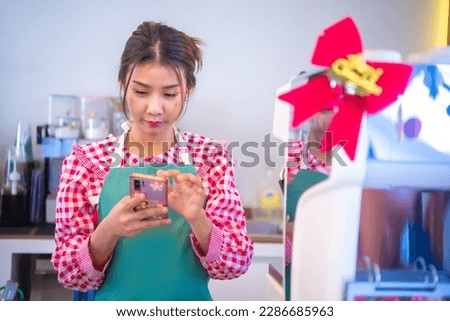 Pretty asian cashier was using a phone application to manage customer transactions, Smart technology, Bussiness and finance.