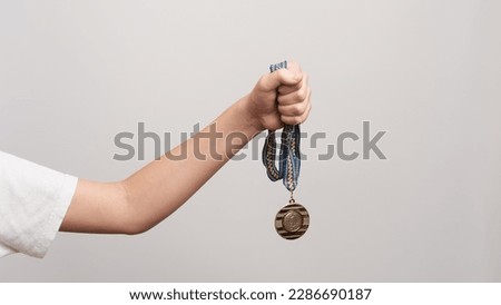 The hand of a young athlete holds golden medal as a symbol of victory