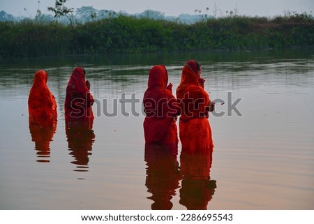 Hindu devotee offering prayers to sun god standing in water according to hindu rituals during Chhath Puja Festival. Chath Puja rituals                              Royalty-Free Stock Photo #2286695543