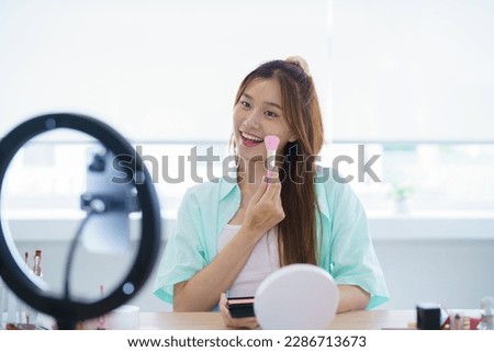 Beauty influencer Asian girl makeup artist applying powder foundation by brush. Beauty influencer asian girl video online marketing live streaming 
