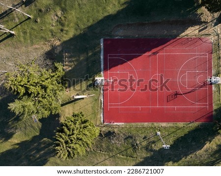 Basketball court from above. Outdoor field activity from top view. Birds eye. White lines and green grass. Aerial image from drone. People gathering places.
