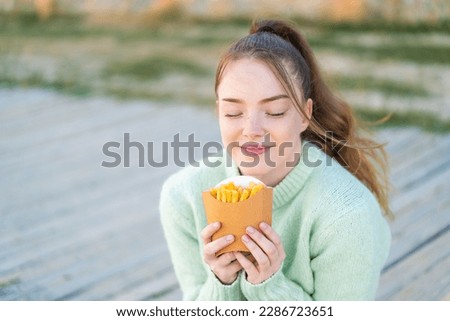 Young pretty girl at outdoors taking fried chips