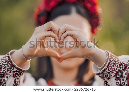 Ukrainian woman in traditional embroidery vyshyvanka dress making sign of shape heart. Ukraine, volunteering, donation help and love concept. High quality photo Royalty-Free Stock Photo #2286726715