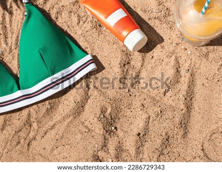 Bright summer beach vacation or travel lifestyle concept flat lay with lemonade and a plastic bag on the sand. Top view. Copy space	