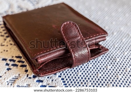 A brown wallet lying on a table on a white tablecloth, The concept of home budget and finance, close up