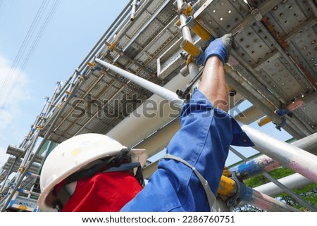Worker's hand holding a wrench to installation scaffolding work for support building construction site of petrochemical plant, oil and gas plant.                               Royalty-Free Stock Photo #2286760751