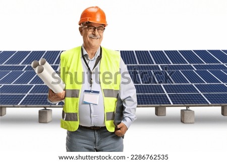 Mature male engineer holding print plans in front of a photovoltaic panels isolated on white background