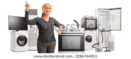 Happy mature woman posing with home applances and pointing up isolated on white background