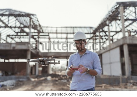 Drone inspecting construction building with operating by professional Architect. Asian man Architect operating drone for aerial view survey inspecting construction.