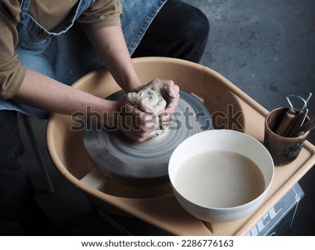 Young female master working on a potter’s wheel, creates clay dishes. Ceramist young woman making clay product on pottery wheel in her cozy studio. Small business, art, hobby, handcraft concept.	
 Royalty-Free Stock Photo #2286776163