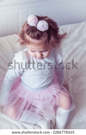 Beautiful little happy smiling baby girl in pink tutu skirt playing at home with balloon