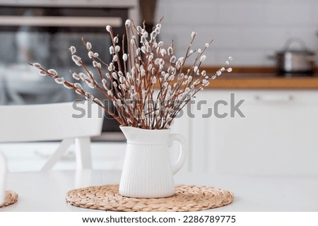 A bouquet of Willow twigs for the Orthodox holiday Palm Sunday. Willow in a white jug in the interior of a modern white kitchen Royalty-Free Stock Photo #2286789775