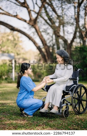Asian young caregiver nurse support senior older male walking outdoors. Specialis doctor help and take care of elderly mature. Nursing home hospital garden concept.
