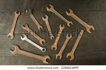 On a wooden background there are many different wrenches, of different sizes.  Conceptual construction and hand tools.  Flat lay, top view.