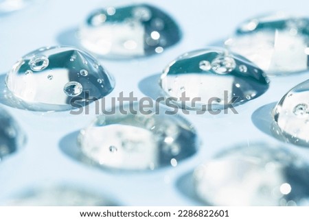 Cosmetic texture, transparent drops of hyaluron, peptide, serum on a blue background. Royalty-Free Stock Photo #2286822601