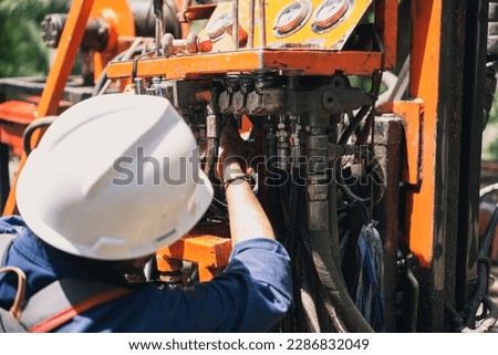 mechanic repairing hydraulic hose in drilling machine, exploration drilling Royalty-Free Stock Photo #2286832049