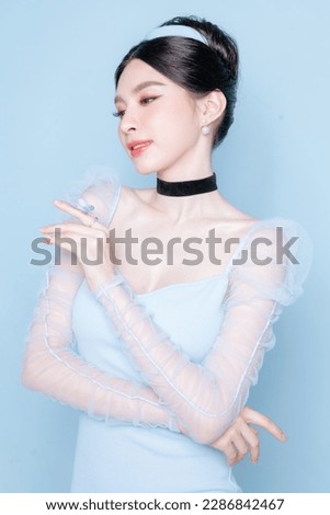 Princess concept. Asian woman with korean makeup on face have plump lips and clean fresh skin on isolated blue background. Portrait of cute female model in studio. Facial treatment, Cosmetology. Royalty-Free Stock Photo #2286842467