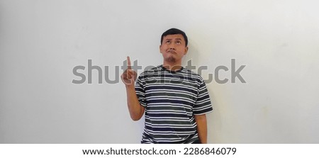 happy indonesian man wearing stripes t-shirt pointing the somthing, asian man pointing the object or showing the something