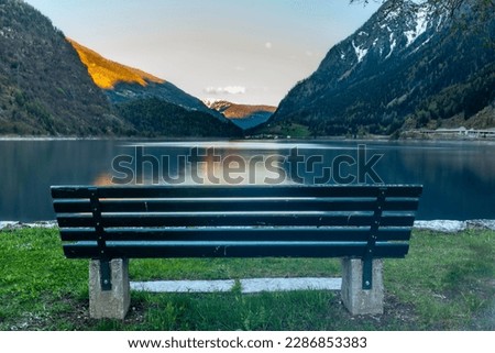 The mountains reflecting in the lake of Poschiavo in Switzerland during a colorful Sunset
