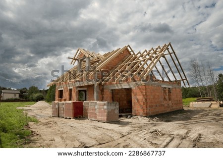 Single-family house construction site. Construction of a brick house with a wooden roof truss. Royalty-Free Stock Photo #2286867737