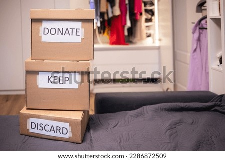 No people clothes are sorting into three boxes that stand on top of each other against the backdrop of an open minimalist wardrobe. Concept: minimalism, decluttering, charity, reuse zero waste Royalty-Free Stock Photo #2286872509