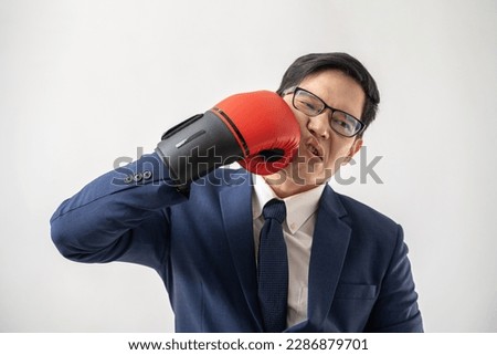 Portrait of confident Asian businessman wearing a boxing mitt isolated on white background