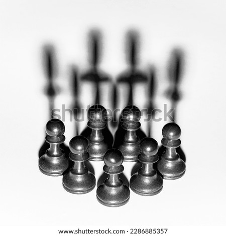 Pawns in formation with shadows projecting an image of a crown