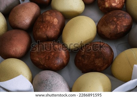 Easter eggs painted with natural food coloring on a white cloth napkin on a dish, close-up
