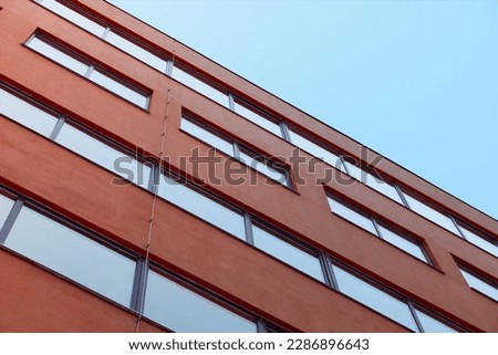 Real estate, architecture, building. A minimalist, simple Nordic modern style of a red terracotta building against a clear blue sky. Style emphasizing functionality while incorporating natural element