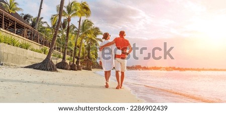 Couple in love hugging while walking on a sandy exotic beach. They have an evening walk by Trou-aux-Biches seashore on Mauritius island. People relationship and tropic honeymoon vacations concept Royalty-Free Stock Photo #2286902439