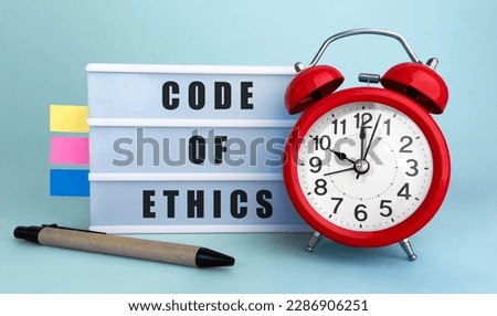 Text Code of Ethics written on the lightbox with alarm clock and colorfull stickers on blue background