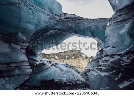 trou tunelle dans une grotte de glace avec vue sur une montagne glacier avec glace et sable volcanique à Myrdalsherppur big glacier and ice cave in iceland
