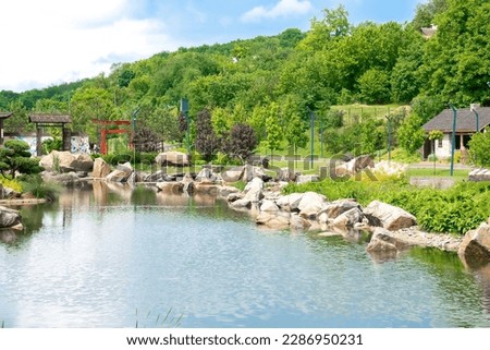 Beautiful green botanical landscape design in garden, city park with trees, bushes and benches, wooden gazebo, decorative lake pond,fresh grass lawn. Scenic summer gardening nature background,concept