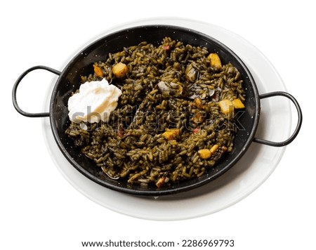 Appetizing racy seafood black paella Arroz negro with squid ink, cuttlefish, mussels and cubanelle peppers. Traditional Valencian cuisine. Isolated over white background Royalty-Free Stock Photo #2286969793