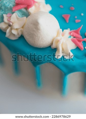 studio shot of chocolate frosted blue dripped icing white cup cake, unicorn , meringue and sprinkles on top