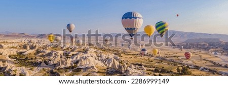 BANNER, LONG FORMAT Colorful hot air balloons flying over at fairy chimneys valley in Nevsehir, Goreme, Cappadocia Turkey. Spectacular panoramic drone view of the underground city and ballooning