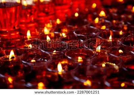 Close-up photo of a lot of red candles in glasses burning in a Chinese Taoist shrine at night. The flames of the candles create a sacred atmosphere for those who came to pray and participate in ritual Royalty-Free Stock Photo #2287001251