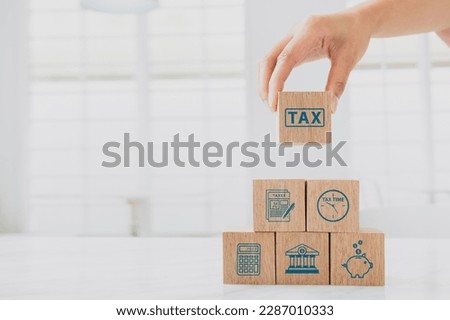 Woman hand hold wooden block with tax icon. Calculation tax return, vat, personal income tax, tax payment. Business and finance concept.  Royalty-Free Stock Photo #2287010333