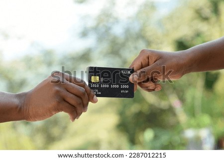 Close up of African American female hands exchanging a payment with a bank credit card. Detailed photo of a woman passing a payment credit card to the saleswoman.